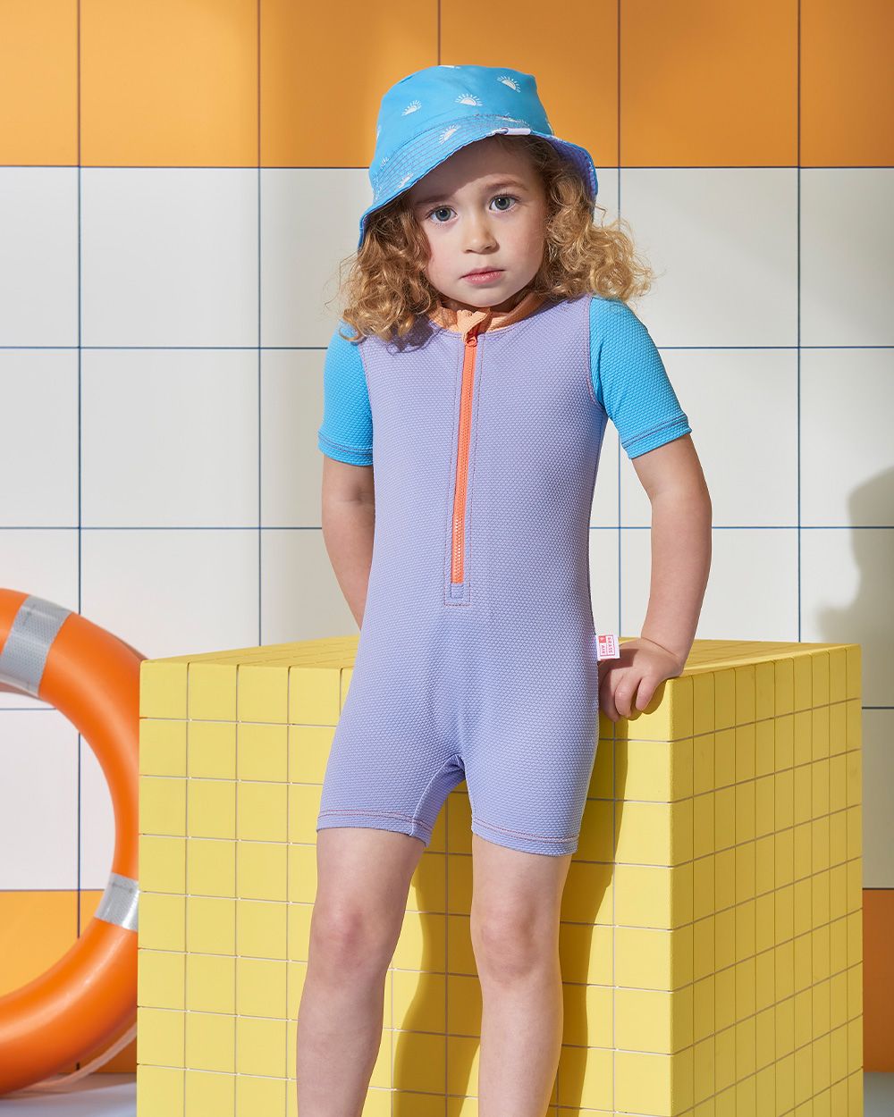 Girl wearing purple swimsuit and blue hat on photoshoot